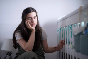 sad mother near crib - Teletherapy Group